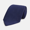 View 1 of product The Long Navy Herringbone Silk Tie by Turnbull & Asser is shown rolled up on a plain white background, highlighting its subtle herringbone weave and luxurious silk fabric.