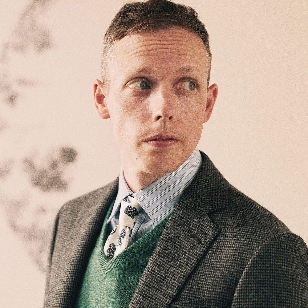 The Turnbull & Asser Charcoal Houndstooth Flannel Jacket features pure wool, a notched lapel, two front buttons, flap pockets, and buttoned cuffs, shown on a white background.