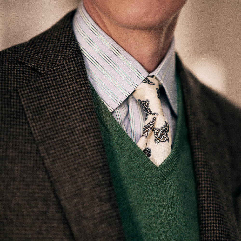The Ecru Paisley Floral Cotton Silk Blend Tie by Turnbull & Asser features a paisley floral pattern, elegantly displayed and neatly rolled on a plain white background.