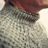 View 3 of product The Turnbull & Asser Merino Knitted Raglan Sleeve Crewneck Jumper in gray features intricate front and sleeve knit patterns, a high neckline, and long sleeves—an essential piece of men’s knitwear. Laid flat on a white background.