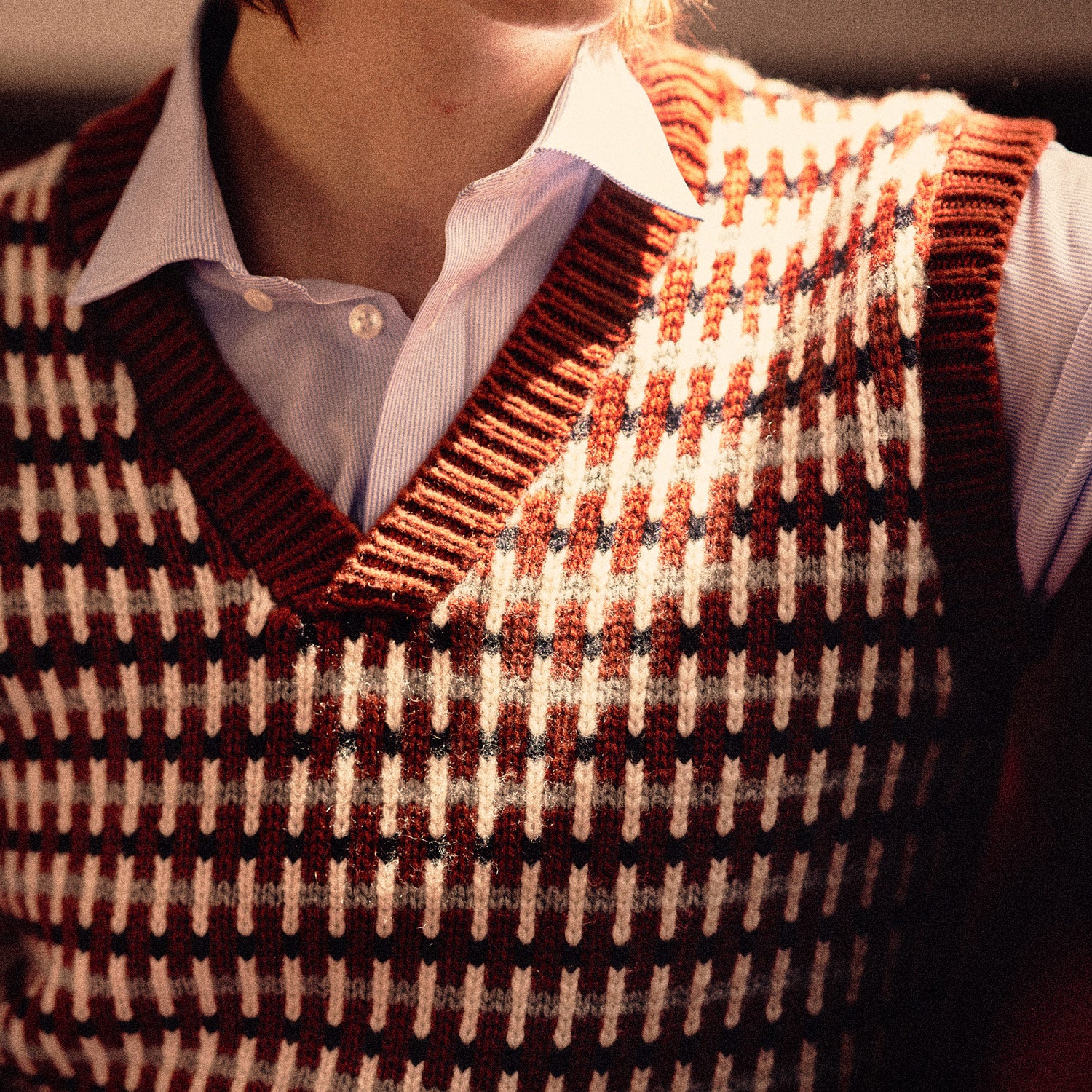 View 3 of product The Rust Knitted Cashmere Slipover by Turnbull & Asser is a sleeveless V-neck vest in red, white, and dark brown houndstooth, inspired by Welsh knitwear with solid red ribbed trim at the collar, armholes, and hem.
