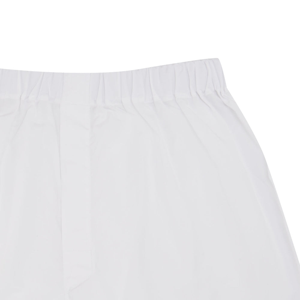 Turnbull & Asser’s White Sea Island Quality Cotton Boxer Shorts, shown flat on a light blue background, offer luxurious comfort with an elastic waistband—a premium underwear choice.