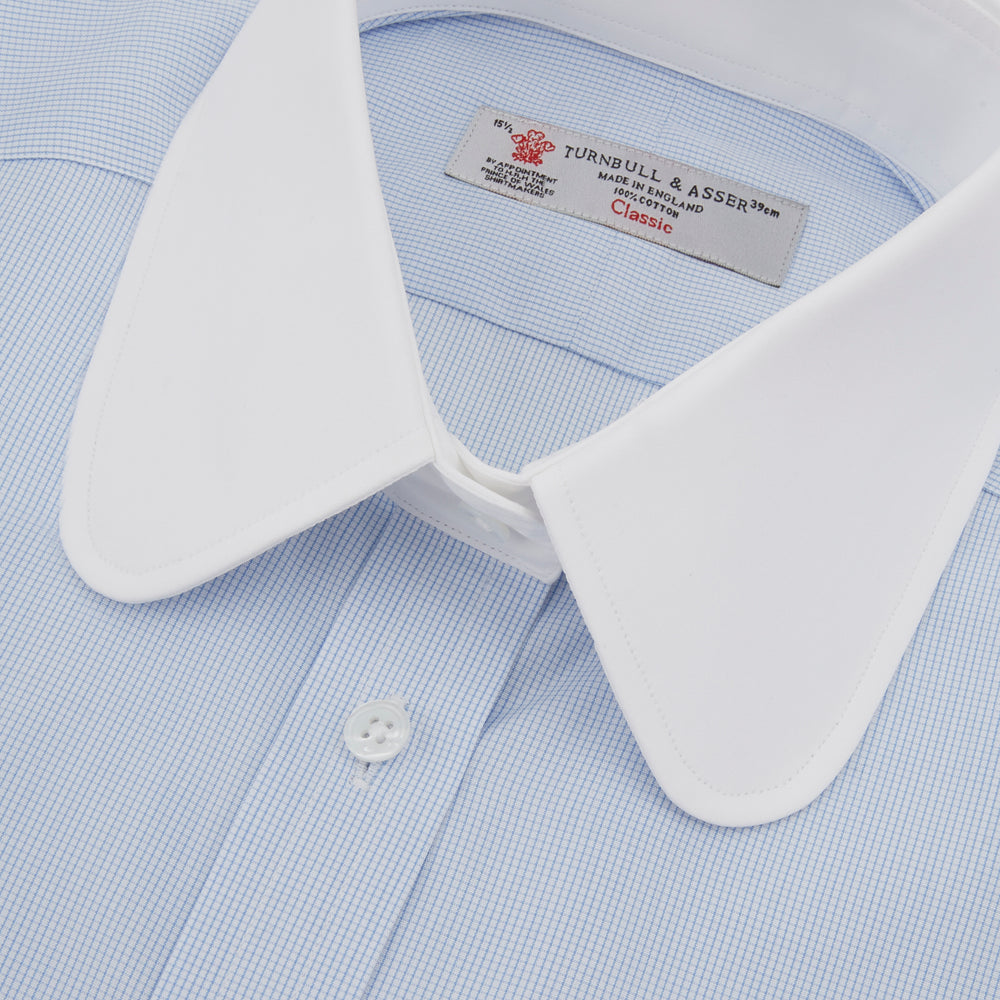 A neatly folded The Great Gatsby Cotton Shirt by Turnbull & Asser, featuring a light blue body, white rounded collar, and double cuffs inspired by 1920s style, displayed on a plain light background.
