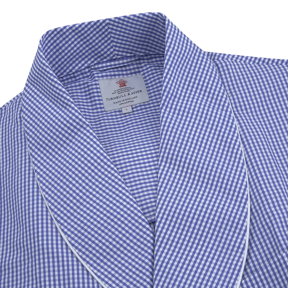 The Turnbull & Asser Mid Blue Gingham Check Piped Cotton Gown, featuring a shawl collar and tied belt, is elegantly displayed against a white background.