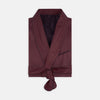 View 1 of product The Turnbull & Asser Burgundy Piped Silk Spot Gown features small white polka dots, a shawl collar, fabric belt, and chest pocket—luxurious nightwear and a stylish men’s statement piece—shown on a white background.