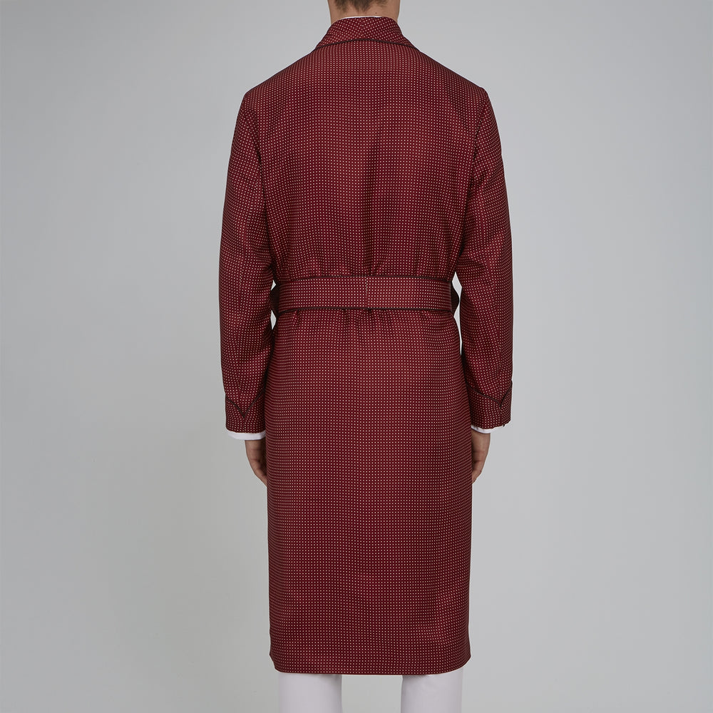 The Turnbull & Asser Burgundy Piped Silk Spot Gown features small white polka dots, a shawl collar, fabric belt, and chest pocket—luxurious nightwear and a stylish men’s statement piece—shown on a white background.