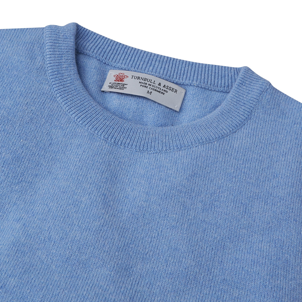 The Turnbull & Asser Sky Blue Fine Cashmere Crew Neck Jumper features long sleeves with ribbed cuffs and hem, shown against a plain white background.