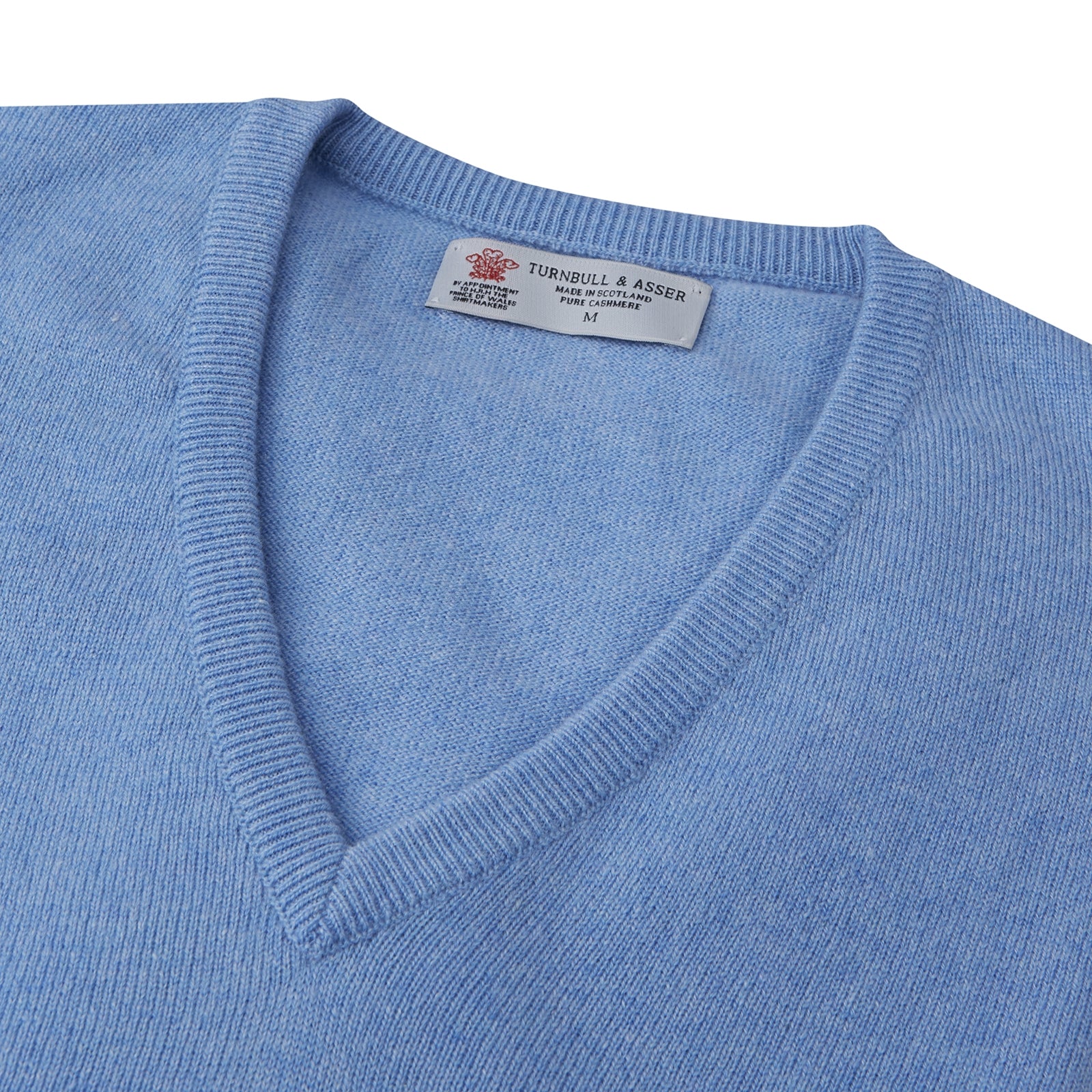 View 2 of product A Sky Blue Fine Cashmere V-Neck Jumper by Turnbull & Asser, neatly folded with visible ribbed collar and cuff, is displayed on a white background. The label appears inside the collar.