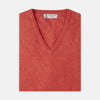 View 1 of product A folded Crimson Fine Cashmere Slipover by Turnbull & Asser in coral-red is shown against a white background, with the visible neckline label highlighting its premium Scottish cashmere quality.