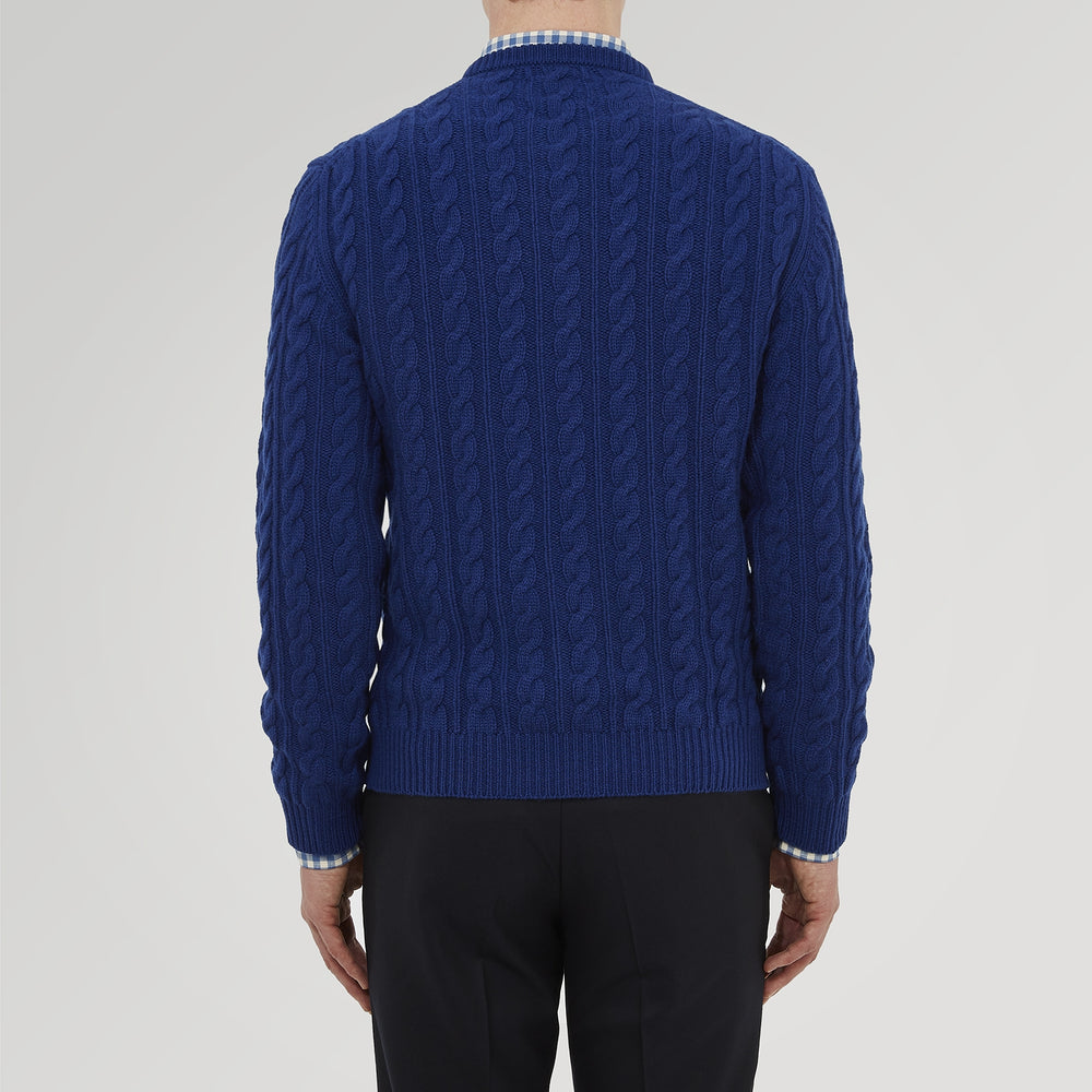 The Blue Crew Neck Cable Knit Cashmere Jumper by Turnbull & Asser features a chunky cable knit, ribbed crew neck and cuffs, and a visible label inside the collar.