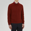 View 2 of product The Harissa Crew Neck Cable Knit Cashmere Jumper by Turnbull & Asser features a chunky, folded cable knit in deep harissa, with ribbed crew neckline and cuffs, and a signature label on the inside collar.