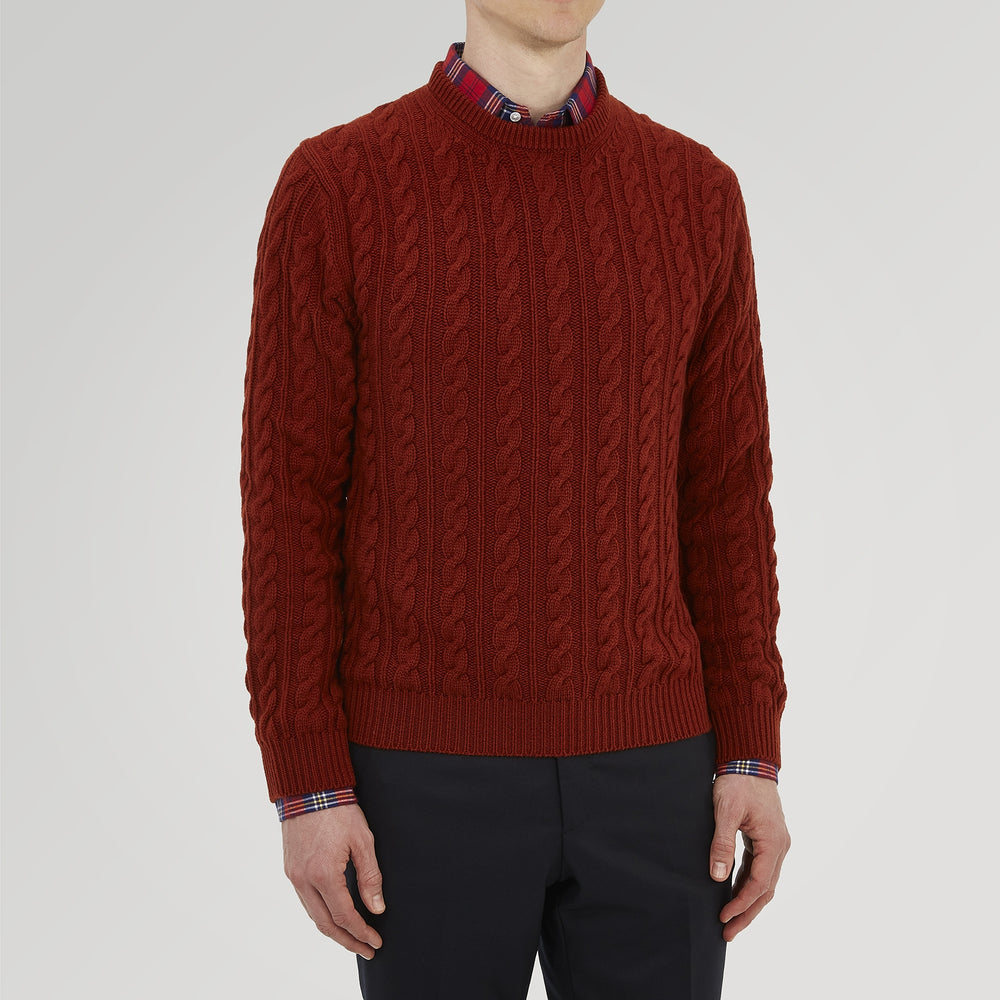 The Harissa Crew Neck Cable Knit Cashmere Jumper by Turnbull & Asser features a chunky, folded cable knit in deep harissa, with ribbed crew neckline and cuffs, and a signature label on the inside collar.