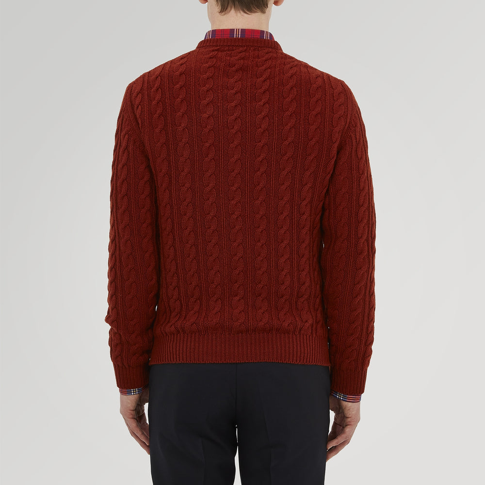 The Harissa Crew Neck Cable Knit Cashmere Jumper by Turnbull & Asser features a chunky, folded cable knit in deep harissa, with ribbed crew neckline and cuffs, and a signature label on the inside collar.