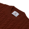 View 4 of product The Harissa Crew Neck Cable Knit Cashmere Jumper by Turnbull & Asser features a chunky, folded cable knit in deep harissa, with ribbed crew neckline and cuffs, and a signature label on the inside collar.