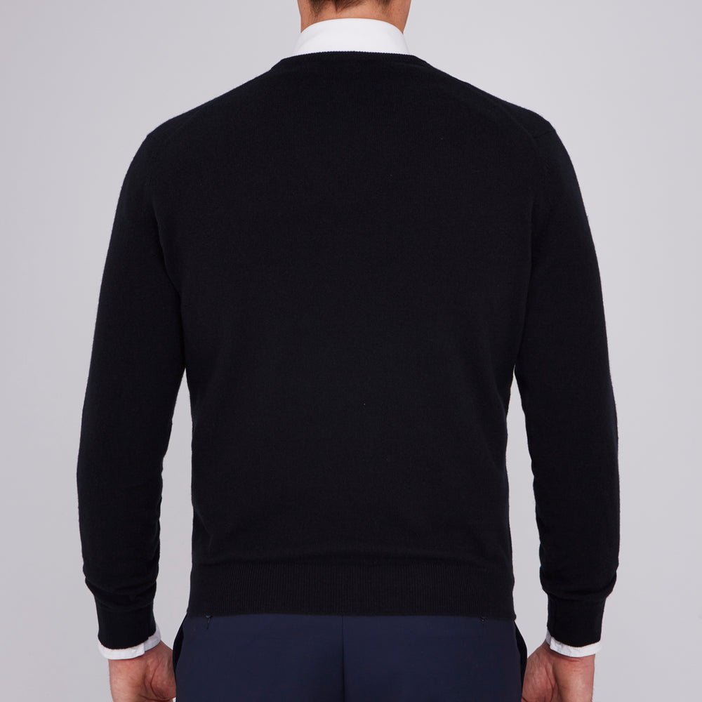 The Turnbull & Asser Black V-Neck Cashmere Jumper is neatly folded, crafted from luxury Scottish cashmere, and features a visible brand label inside the collar, displayed on a plain white background.