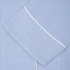 View 2 of product Turnbull & Asser Ladies' Blue Cotton-Cashmere Pyjama Set with white piping features a collared button-up top, neatly folded, and matching drawstring pants laid flat on a plain white background.