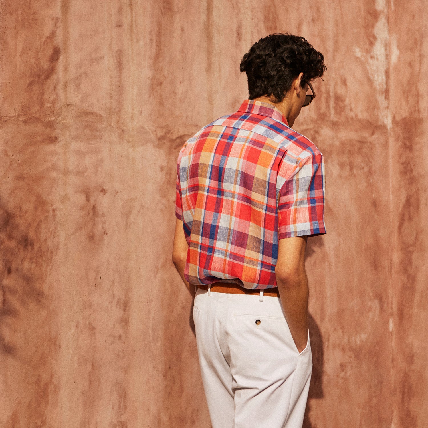 View 3 of product The Turnbull & Asser Red Madras Check Weekend Fit Short Sleeve Linen Shirt features a Dorset collar, white buttons, and a red, blue, white, and beige plaid pattern. Shown on a plain white background.