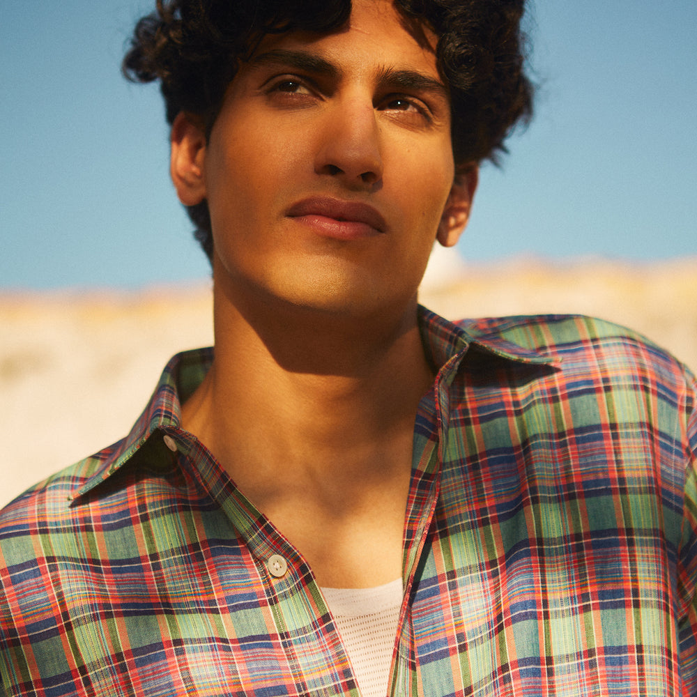 The Turnbull & Asser Green and Red Madras Check Weekend Fit Linen Shirt features a Derby collar, 1-button cuff, and colorful plaid pattern, crafted from sustainable linen and shown against a plain white background.