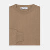 View 1 of product A folded Natural Crew Neck Cashmere Jumper by Turnbull & Asser, in light brown, features a visible brand label and one sleeve neatly laid across the front of this smart casual luxury Scottish sweater.