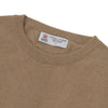 View 4 of product A folded Natural Crew Neck Cashmere Jumper by Turnbull & Asser, in light brown, features a visible brand label and one sleeve neatly laid across the front of this smart casual luxury Scottish sweater.