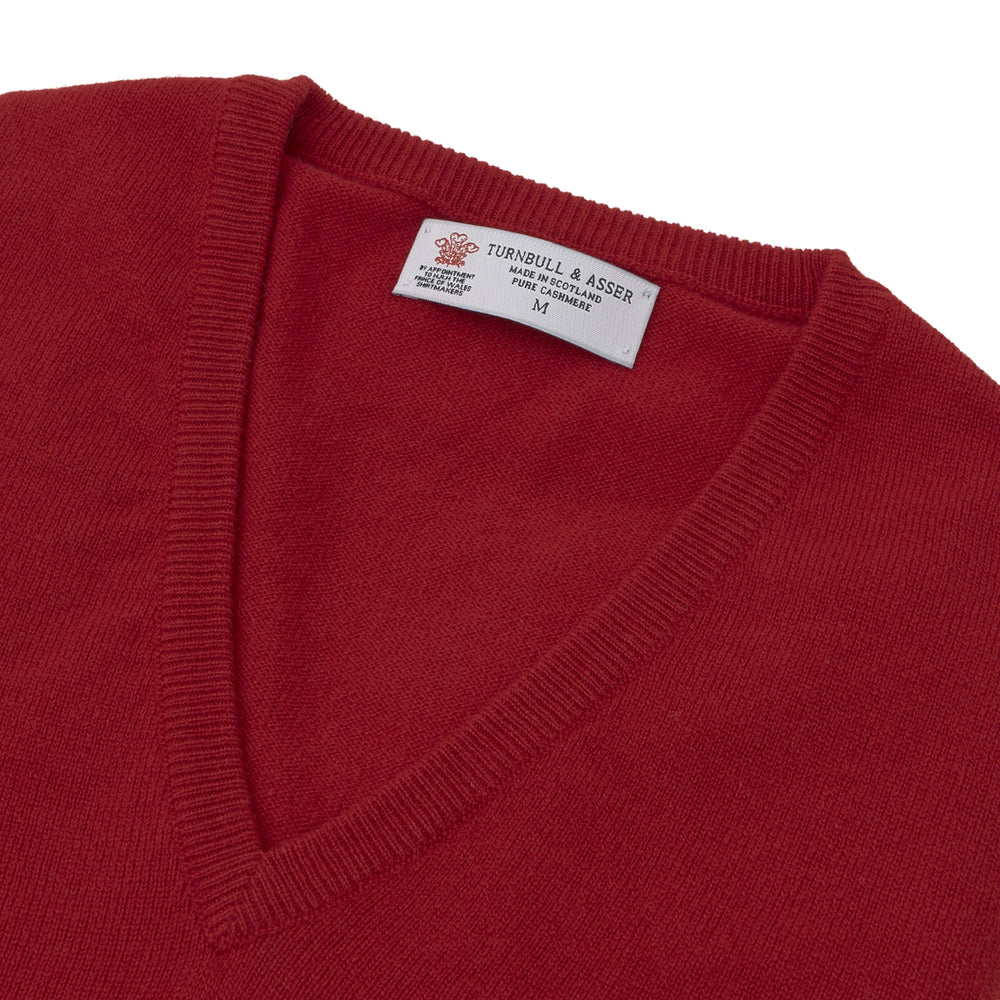 The Deep Red V-Neck Cashmere Jumper by Turnbull & Asser features long sleeves, ribbed cuffs and collar, and an inner collar label. Displayed on a white background, it's ideal for smart casual looks.