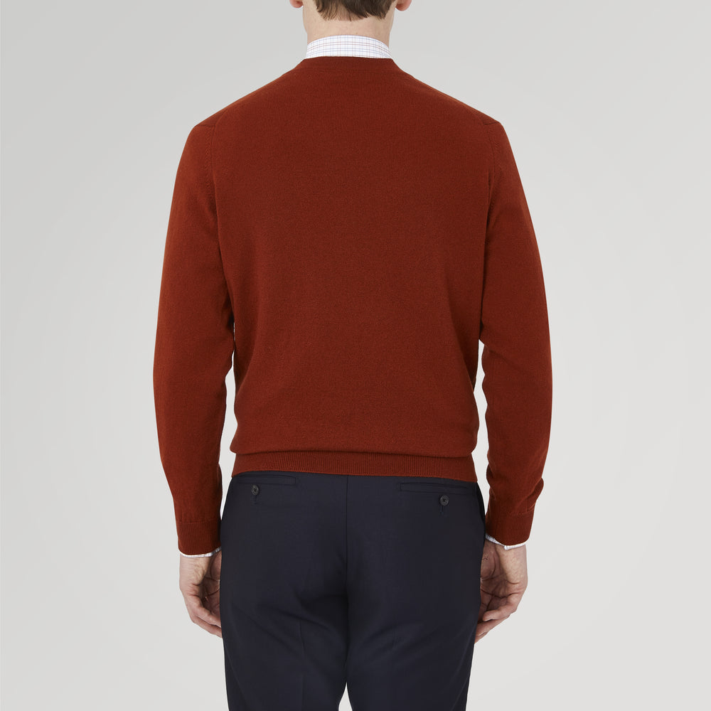 The Harissa Cashmere Cardigan by Turnbull & Asser, in deep red-brown 21GG knit, is folded to display its V-neck, ribbed cuffs, and two buttons against a white background.