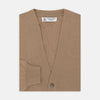 View 1 of product A Natural Cashmere Cardigan by Turnbull & Asser, light brown with a V-neckline, ribbed cuffs, and button closure, is neatly folded and displayed against a white background.
