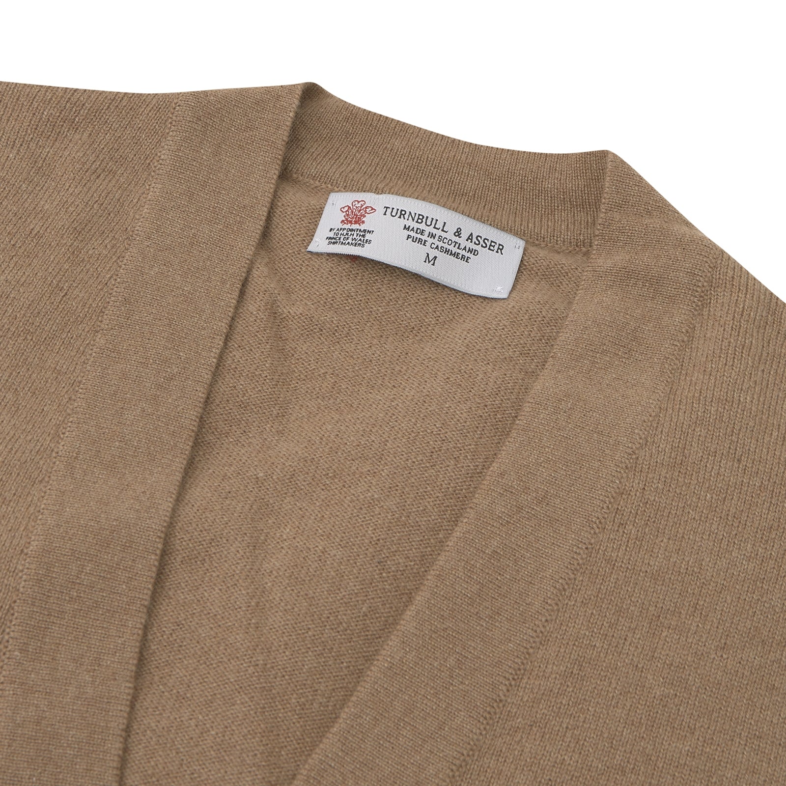 View 2 of product A Natural Cashmere Cardigan by Turnbull & Asser, light brown with a V-neckline, ribbed cuffs, and button closure, is neatly folded and displayed against a white background.