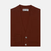 View 1 of product The Harissa Cashmere Cardigan by Turnbull & Asser, in deep red-brown 21GG knit, is folded to display its V-neck, ribbed cuffs, and two buttons against a white background.