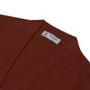 View 4 of product The Harissa Cashmere Cardigan by Turnbull & Asser, in deep red-brown 21GG knit, is folded to display its V-neck, ribbed cuffs, and two buttons against a white background.