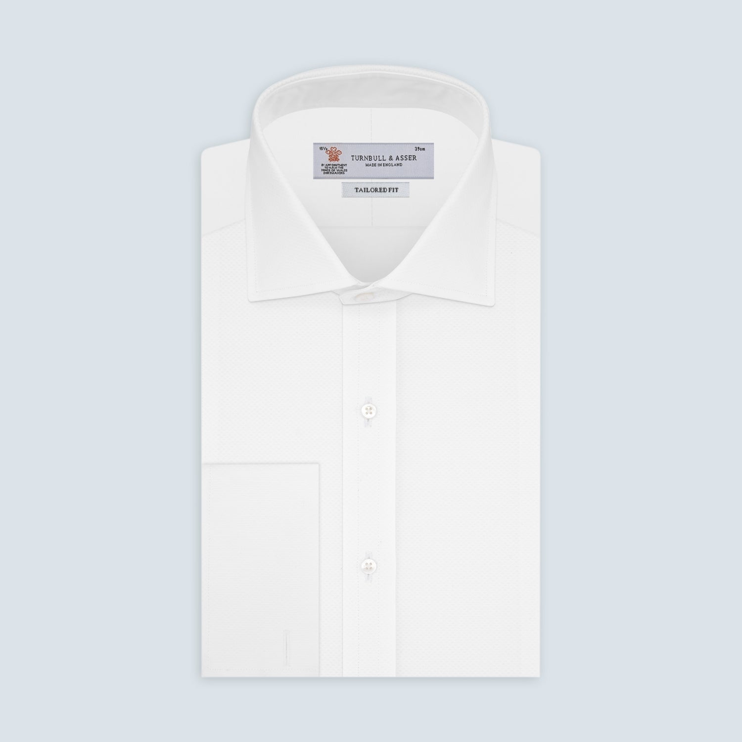 View 1 of product A neatly folded Turnbull & Asser Tailored Fit White Marcella Front Shirt with a Kent collar and double cuffs is displayed against a light grey background, with the label inside the collar visible.