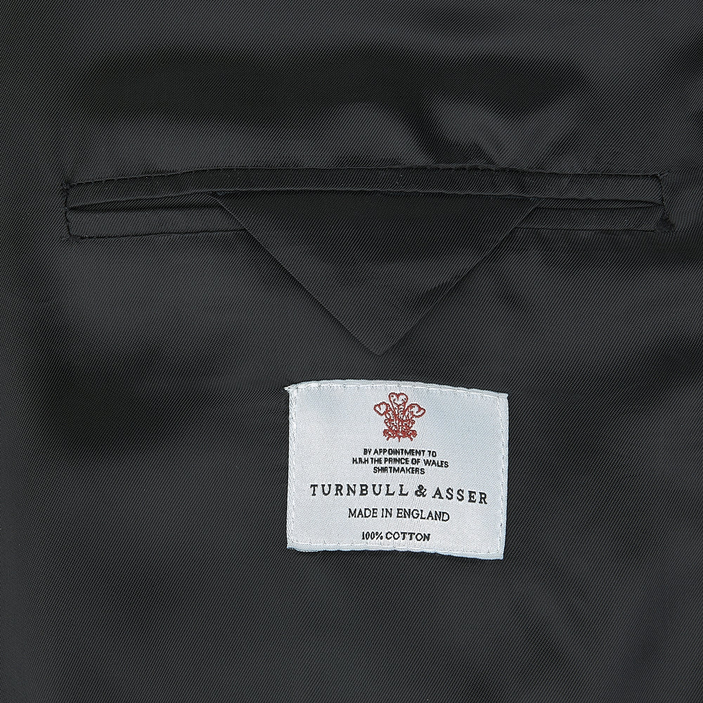 The Turnbull & Asser Black Double Breasted Velvet Smoking Jacket features a shawl collar, decorative frogging closure, and subtle piping on cuffs and edges, ideal for eveningwear and shown against a plain white background.