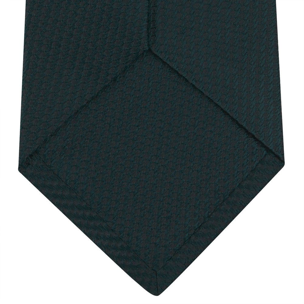 The Turnbull & Asser Forest Green Lace Silk Tie, shown rolled on a white background, features a lace weave texture and brings versatile style to any wardrobe.