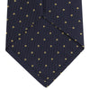 View 4 of product The Turnbull & Asser Navy and Gold Spot Lace Silk Tie, ideal for office wear, is shown rolled up on a white background.