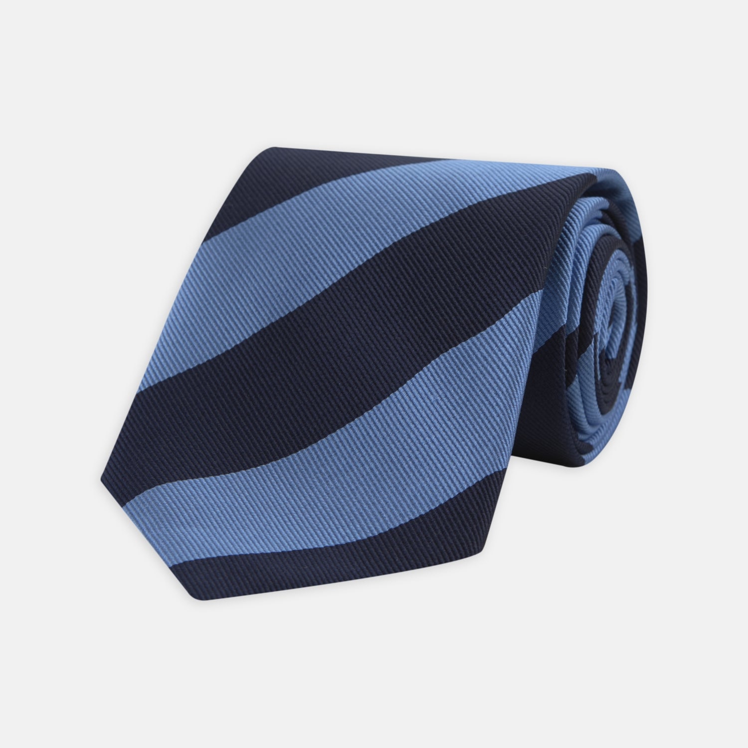 View 1 of product The Turnbull & Asser Navy and Blue Block Stripe Repp Silk Tie features wide navy and blue diagonal stripes on luxurious textured silk, elegantly presented against a white background.