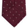 View 4 of product The Turnbull & Asser Burgundy and White Small Spot Herringbone Silk Tie, crafted from fine English silk, is shown rolled up on a plain white background.