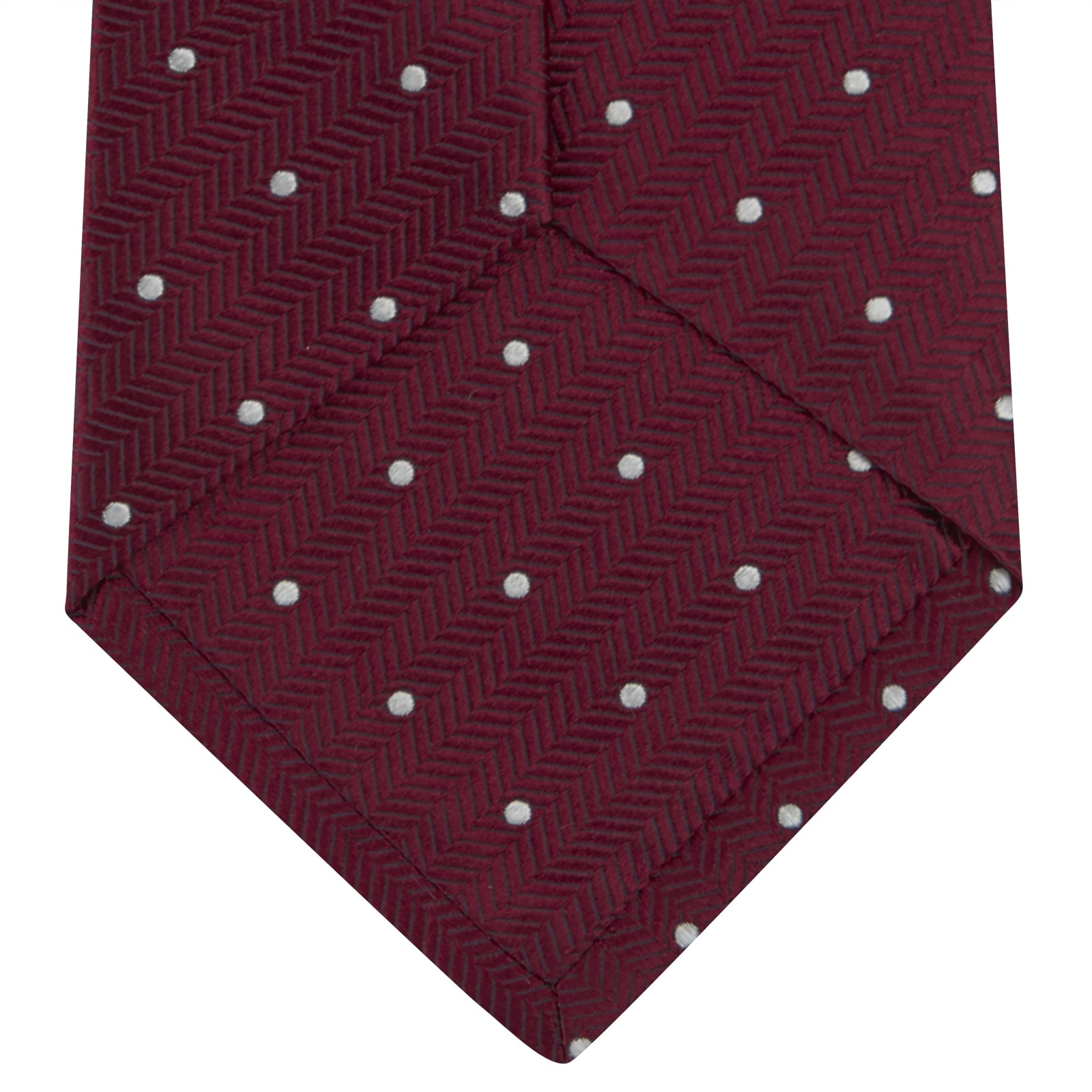 View 4 of product The Turnbull & Asser Burgundy and White Small Spot Herringbone Silk Tie, crafted from fine English silk, is shown rolled up on a plain white background.