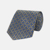 View 1 of product The Gold and Blue Circle and Spot Silk Tie by Turnbull & Asser features blue silk adorned with yellow and white circles and lines, rolled neatly on a light background—an elegant choice for complementing any office shirt.
