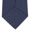 View 4 of product The Turnbull & Asser Navy Floral Spot Silk Tie, featuring a subtle light blue and gray pattern, is rolled up against a plain white background—an ideal accessory for any office shirt.
