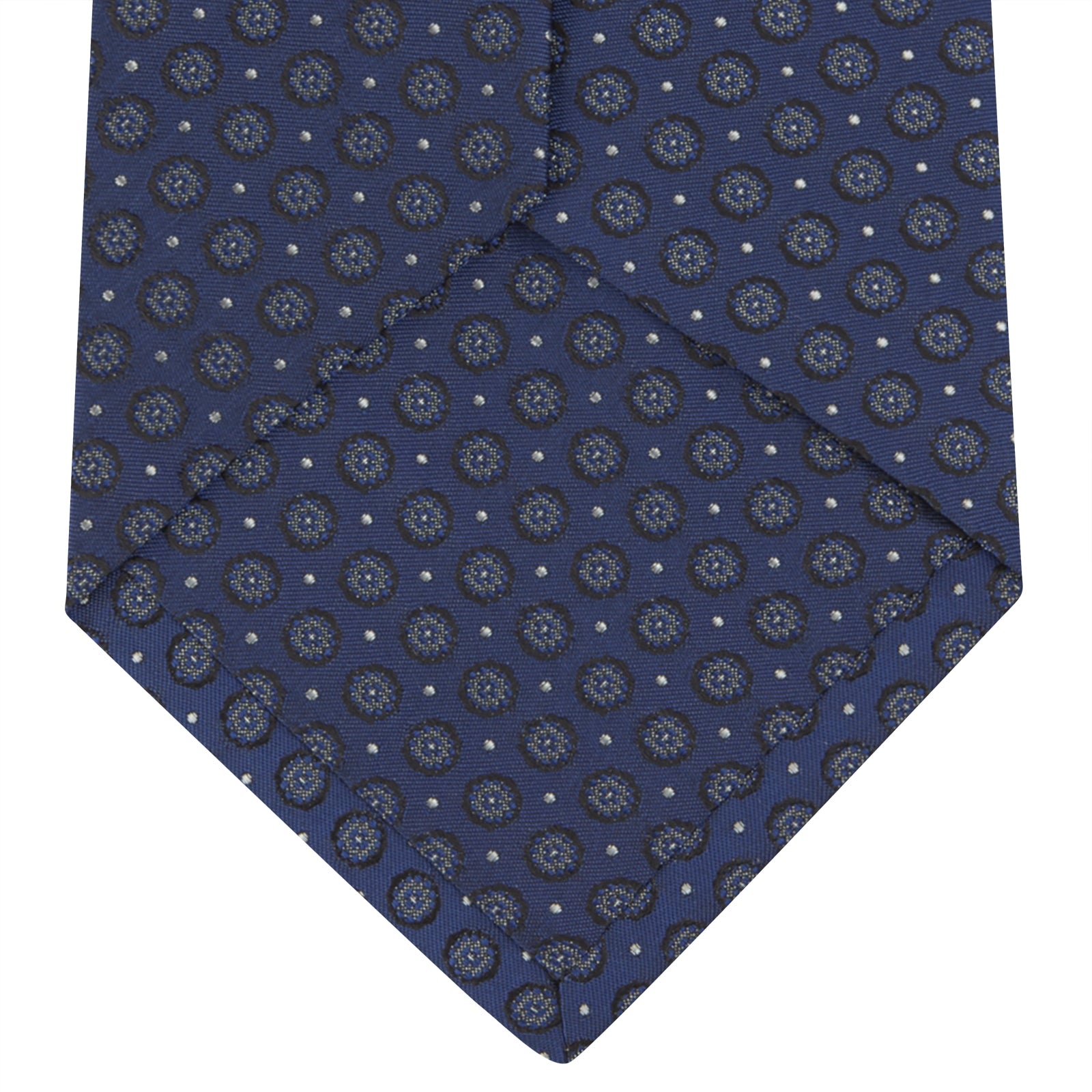 View 4 of product The Turnbull & Asser Navy Floral Spot Silk Tie, featuring a subtle light blue and gray pattern, is rolled up against a plain white background—an ideal accessory for any office shirt.