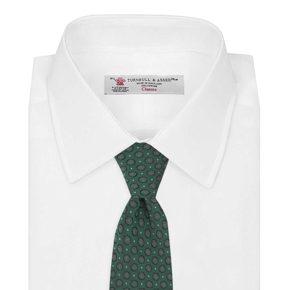 The Turnbull & Asser Green Floral Spot Silk Tie features small, light-colored circular dots on a classic green silk background—ideal for dressing up your favorite office shirt. Displayed rolled on a plain white backdrop.
