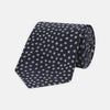 View 1 of product The Turnbull & Asser Navy and White Paint Spot Silk Tie features evenly spaced white spots on classic navy, shown rolled up on a white background—ideal for complementing your favorite office shirt.