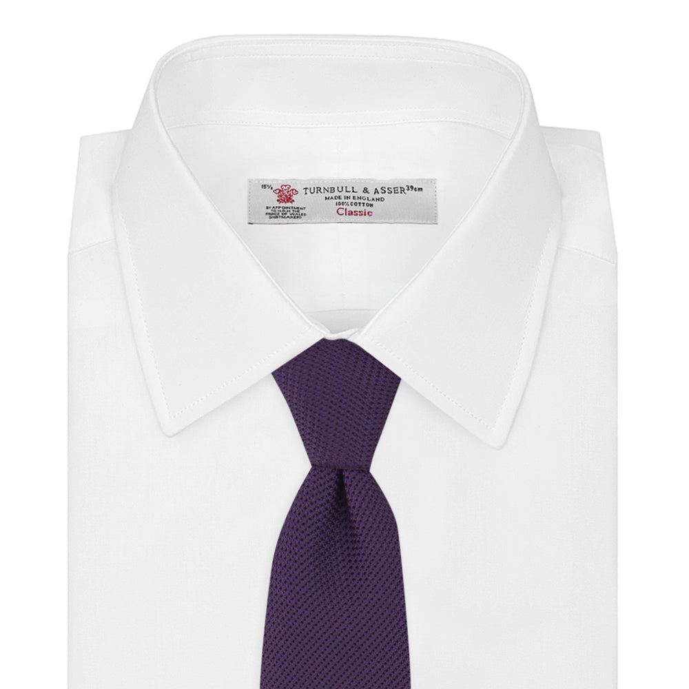 The Turnbull & Asser Plum Grenadine Silk Tie, featuring a textured grenadine weave, is shown rolled up on a plain white background.