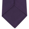 View 4 of product The Turnbull & Asser Plum Grenadine Silk Tie, featuring a textured grenadine weave, is shown rolled up on a plain white background.