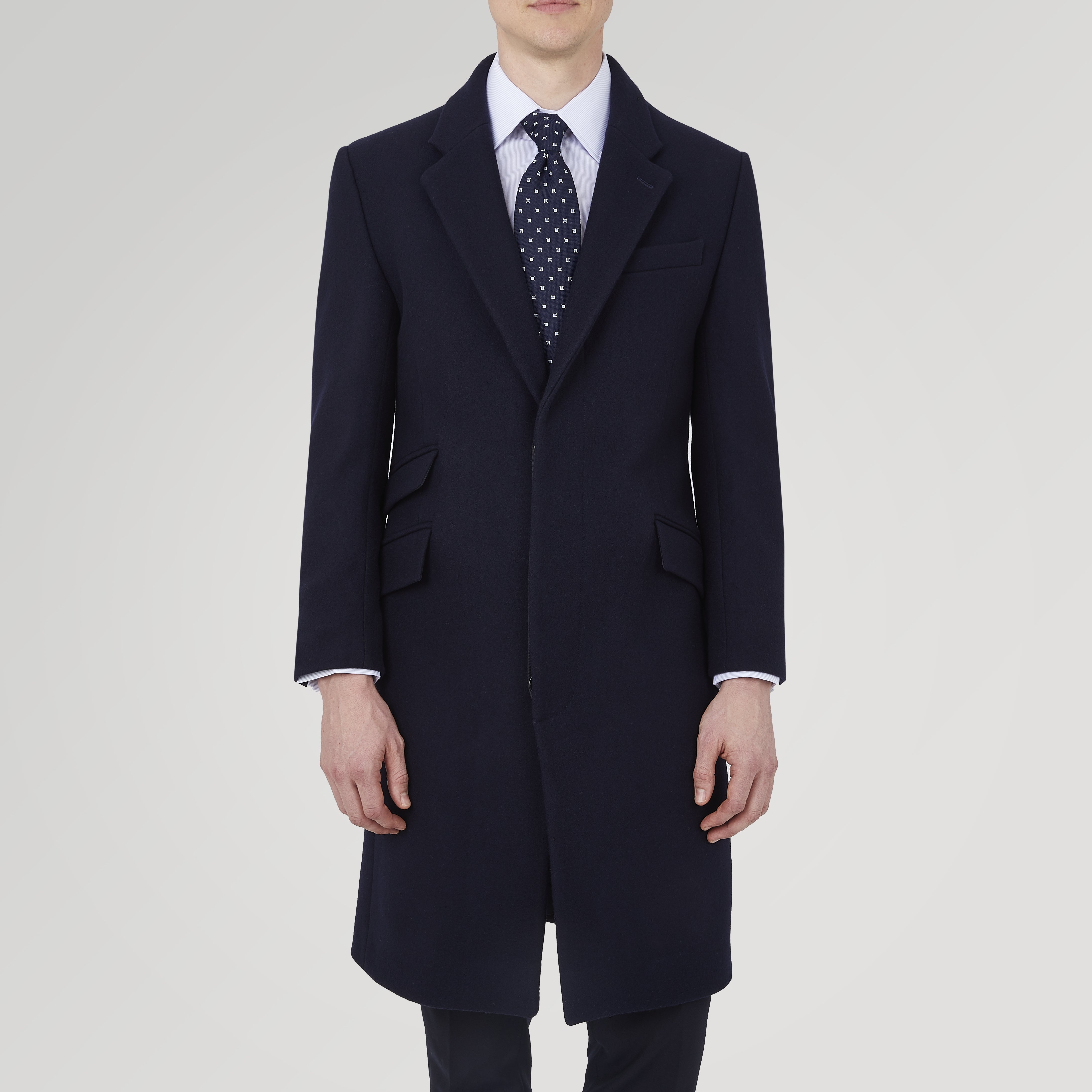 View 2 of product The Turnbull & Asser Navy Lambswool Joseph Overcoat, a men's knee-length coat with notched lapels, a single-breasted front, and three flap pockets per side, is shown against a plain white background.