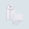 View 1 of product The Turnbull & Asser White Piped Cotton Pyjama Set, made from Egyptian cotton and featuring black piping and two buttons, is shown folded with a matching white tie-strap face mask on a light gray background.