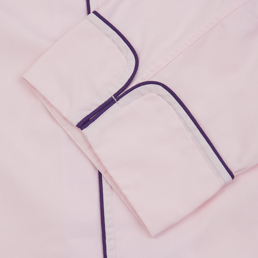 The Turnbull & Asser Pink Piped Cotton Pyjama Set, featuring dark piping on the collar and front with matching pants, is elegantly displayed on a white background—a luxurious sleepwear choice.