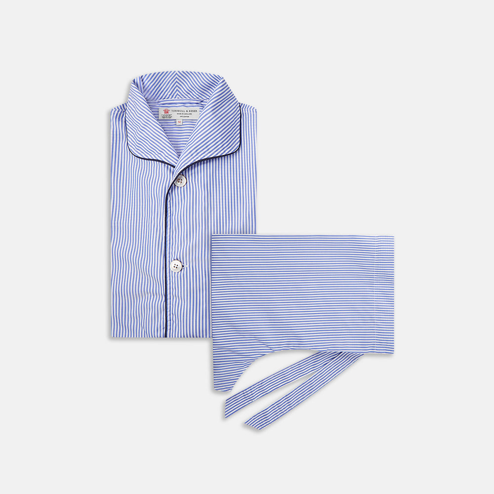 The Turnbull & Asser Blue Bengal Stripe Piped Cotton Pyjama Set, featuring a folded top with white buttons beside matching bottoms, is displayed on a plain light background.