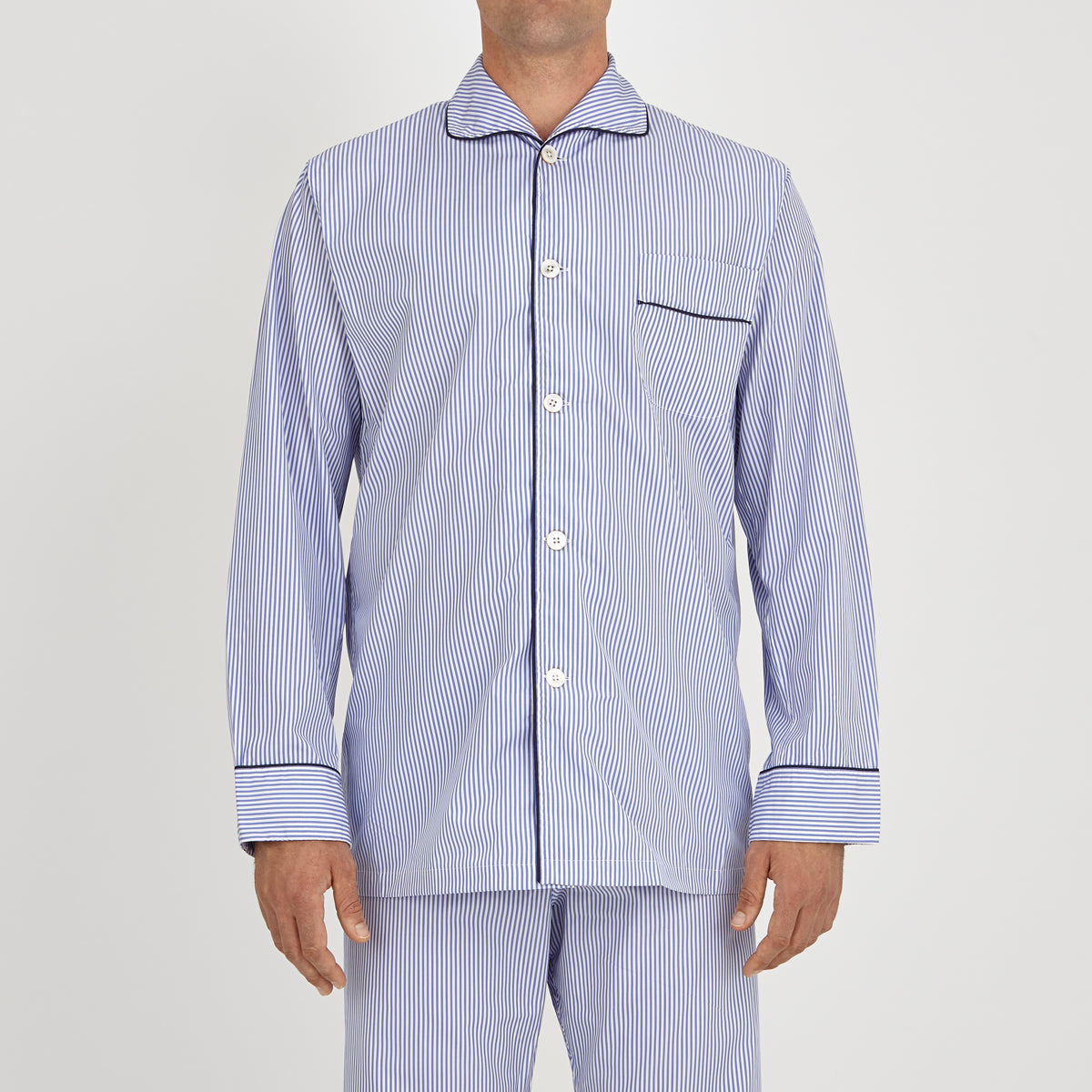 View 2 of product The Turnbull & Asser Blue Bengal Stripe Piped Cotton Pyjama Set, featuring a folded top with white buttons beside matching bottoms, is displayed on a plain light background.