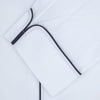 View 2 of product The Turnbull & Asser White Herringbone Piped Superfine Cotton Pyjama Set features a long-sleeve button-up top and drawstring pants with black piping, all crafted from superfine cotton and shown against a plain white background.